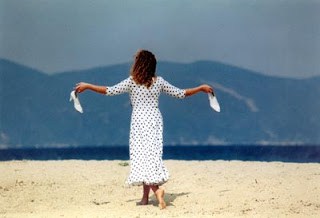 Isabelle Renaud, mujer frente al mar griego con dos pañuelos blancos
