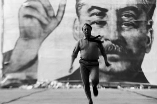 Una persona se aleja aterrorizada de un cartel de Stalin con cuatro ojos