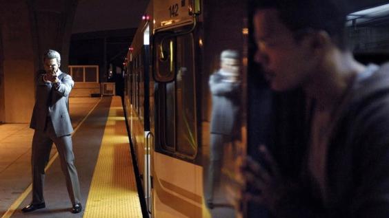 El asesino amaenza con su arma al taxista escondido tras un vagón de metro