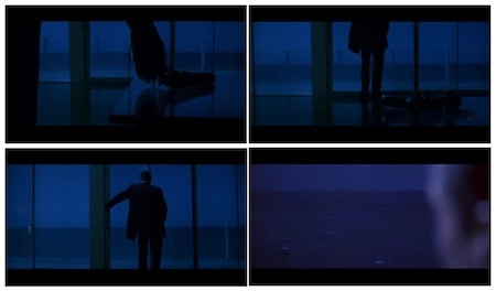 El atracador se acerca a la ventana en plena noche y contempla el océano mientras deja su pistola en una mesa