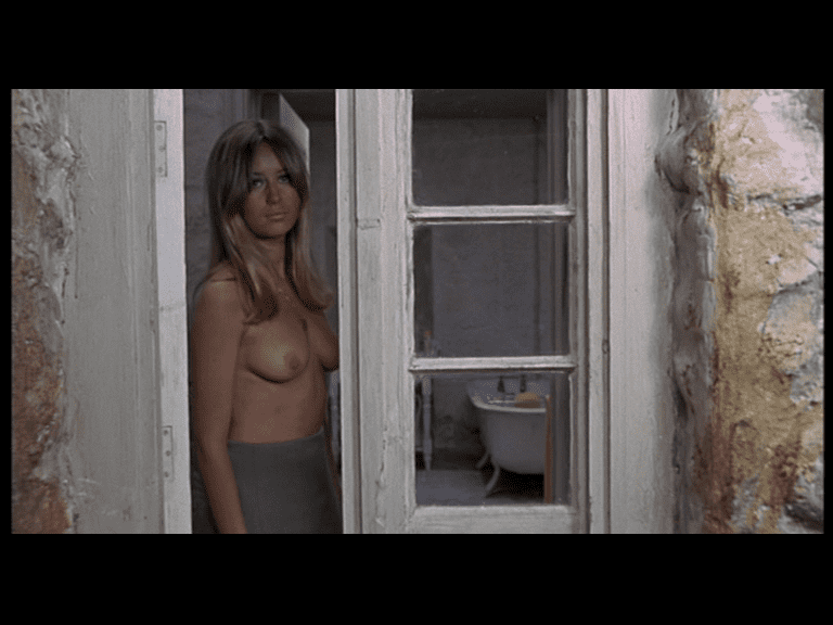 La protagonista mira medio desnuda desde la ventana
