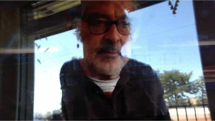 El director mira a través de una ventana con cara de tristeza