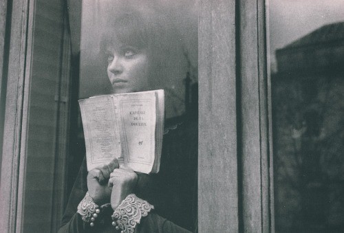 La protagonista mira hacia el exterior desde una ventana con un libro en las manos
