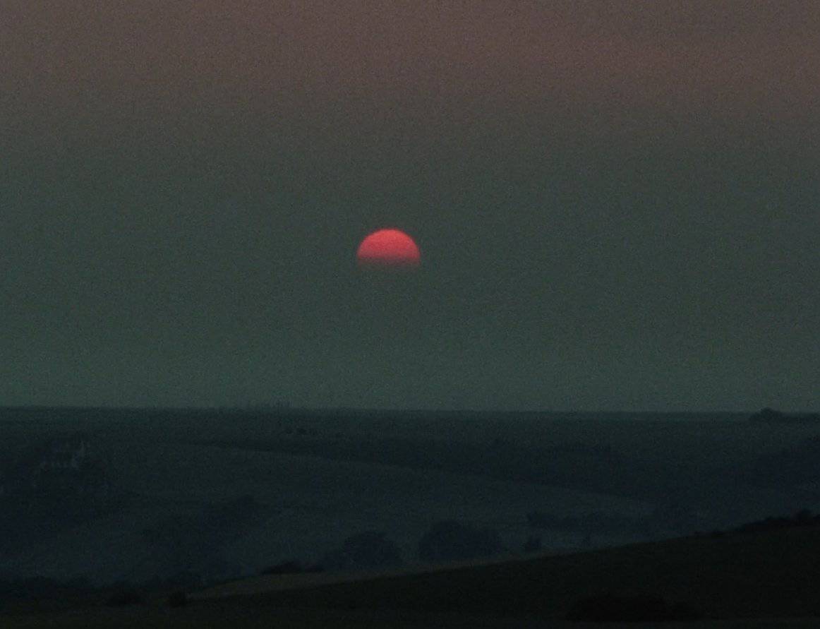 El sol se pone sobre el horizonte de colinas onduladas