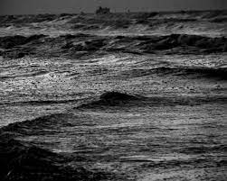 Las olas del mar rompen con fuerza en la playa, en blanco y negro