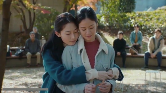 Las dos actrices jóvenes se abrazan mientras representan una escena en el parque
