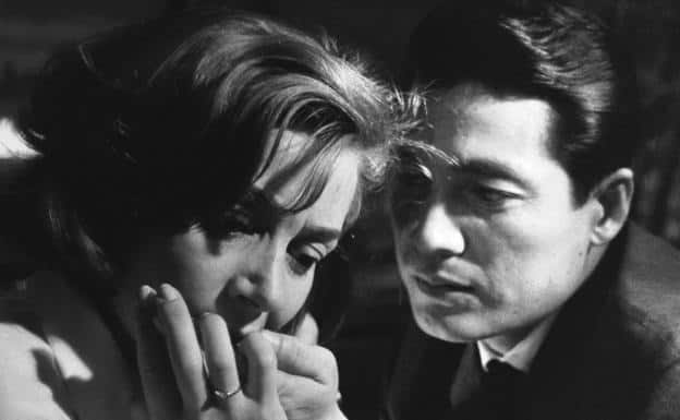 El amante japonés sujeta la barbilla de la amante francesa que le besa la mano
