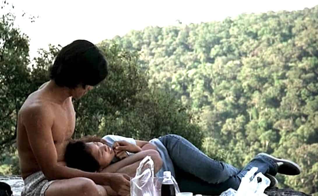La muchacha descansa en brazos del protagonista mientras contemplan el bosque