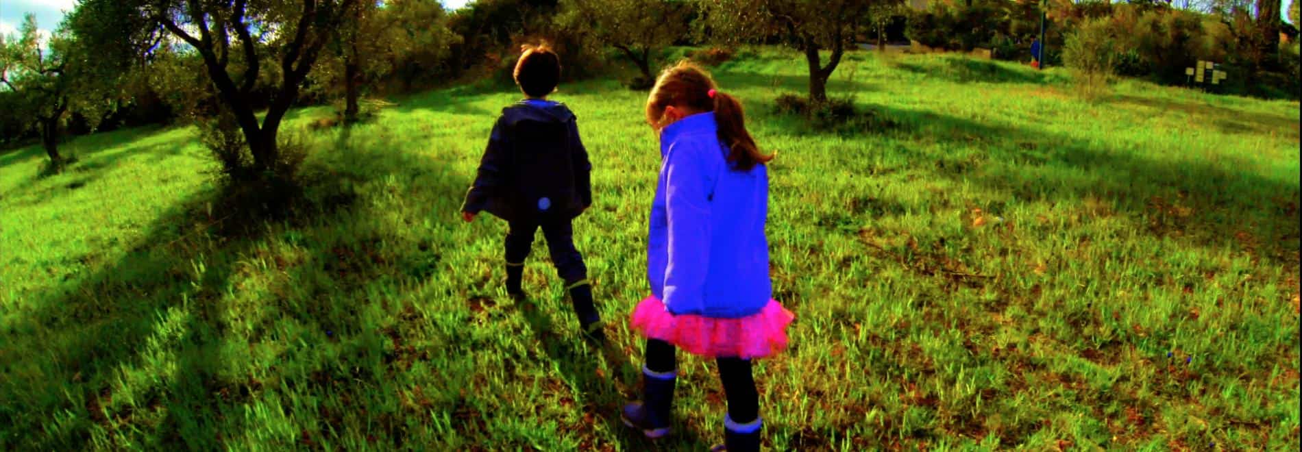 Dos niños con el color muy contratado caminan por un jardín al atardecer