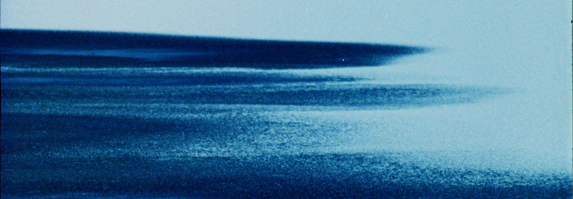 Una playa con agua llegando muy granulada y virada en azul
