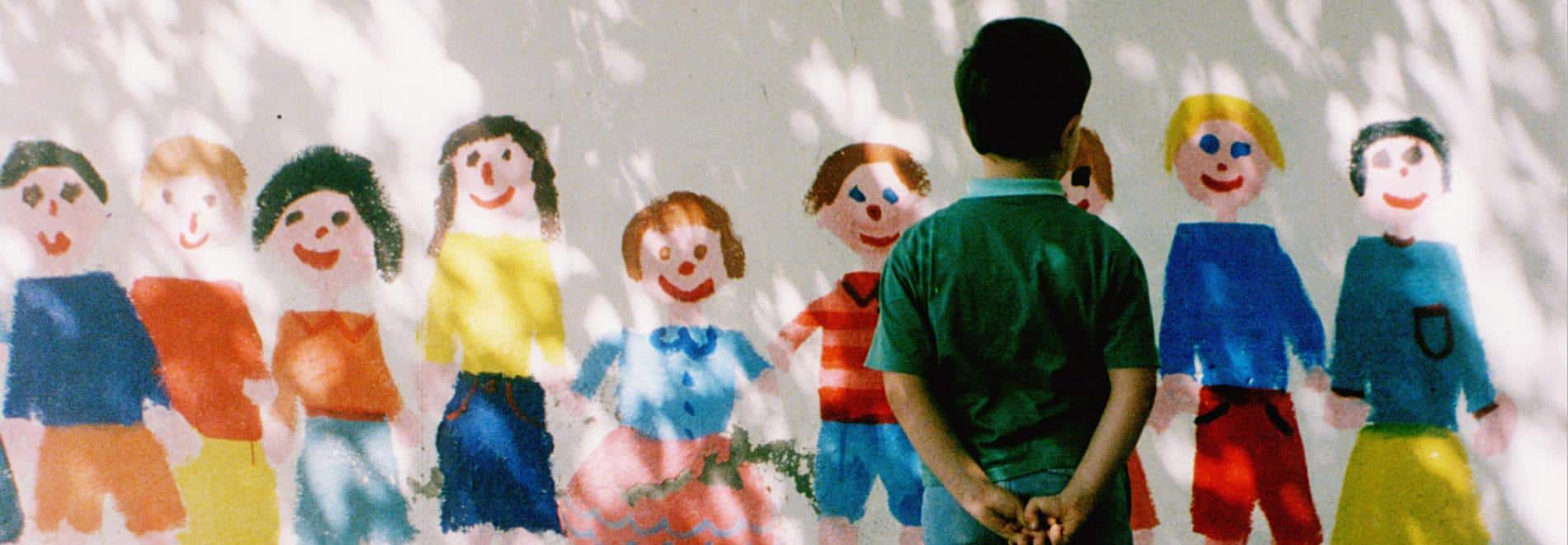 Un niño contempla un mural colorido que representa otros niños
