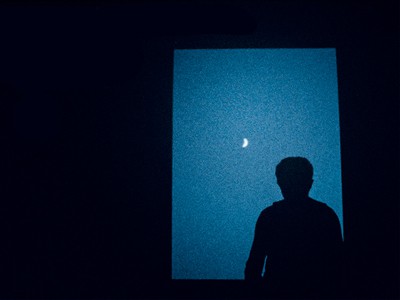 Una persona mira la luna creciente desde su ventana