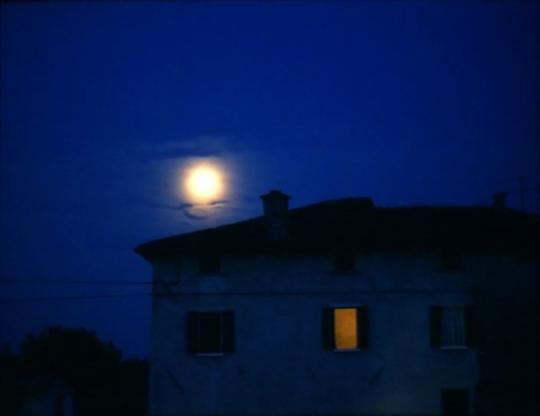 La luna se alza tras la casa iluminada