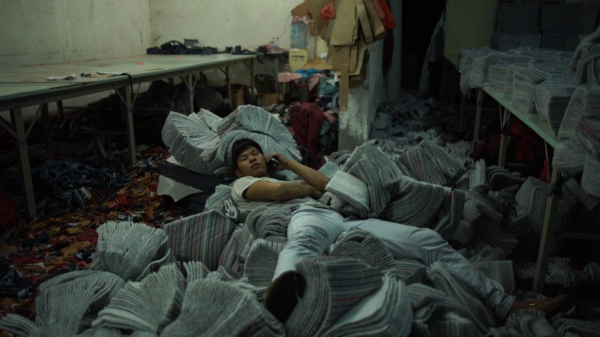Uno de los trabadores textiles duerme sobre fardos de ropa